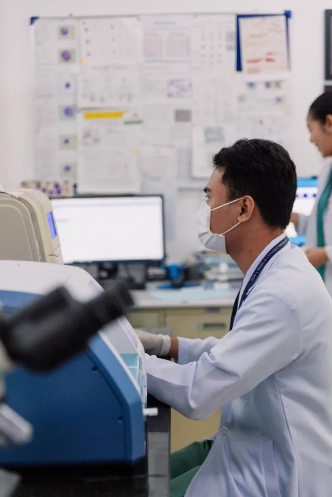 Masked scientist working with laboratory analyzer equipment